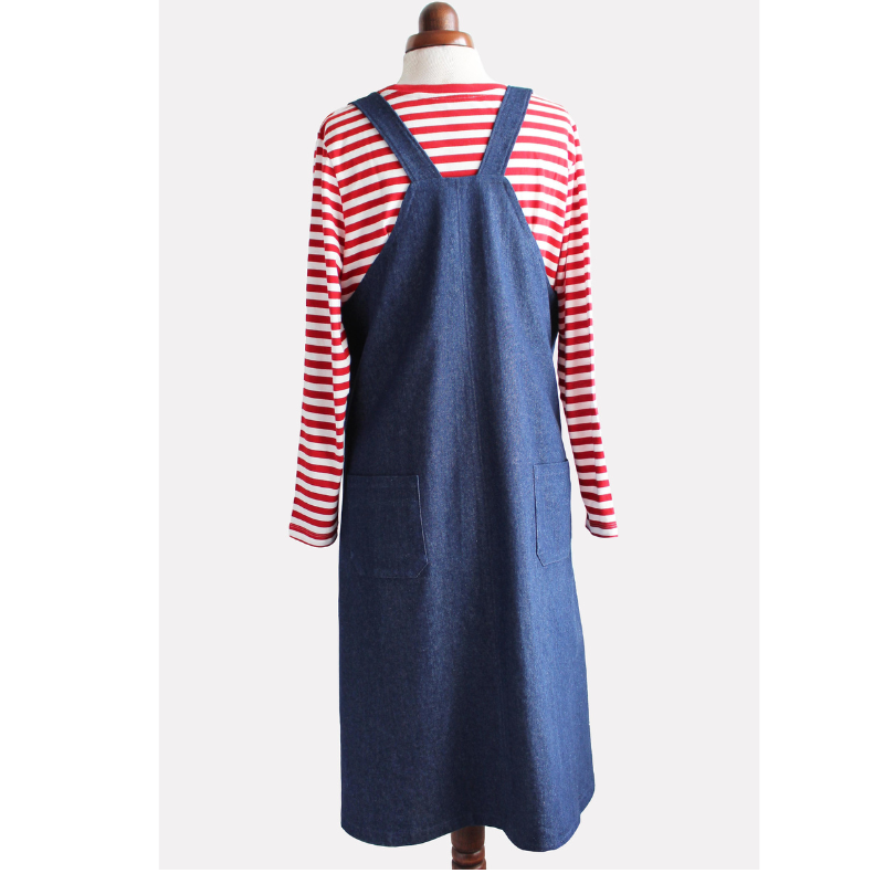 Blue denim pinafore dress over a red and white striped shirt on a mannequin against a white background