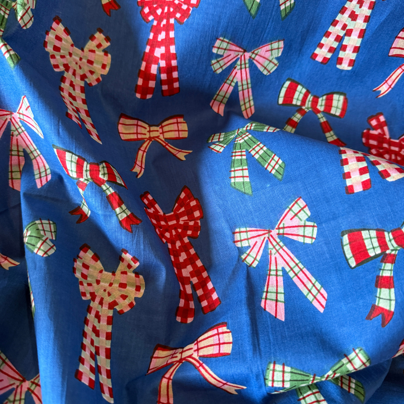 Blue fabric with red, green, and white plaid bows pattern