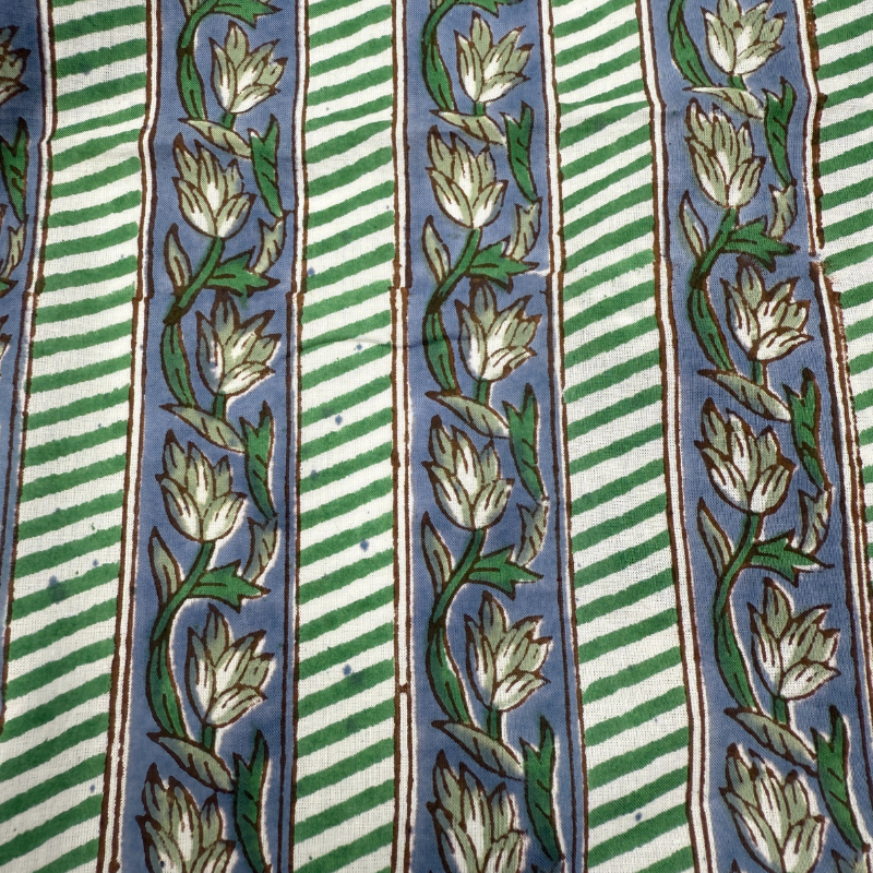 Close-up of fabric with green and white floral patterns on a blue background