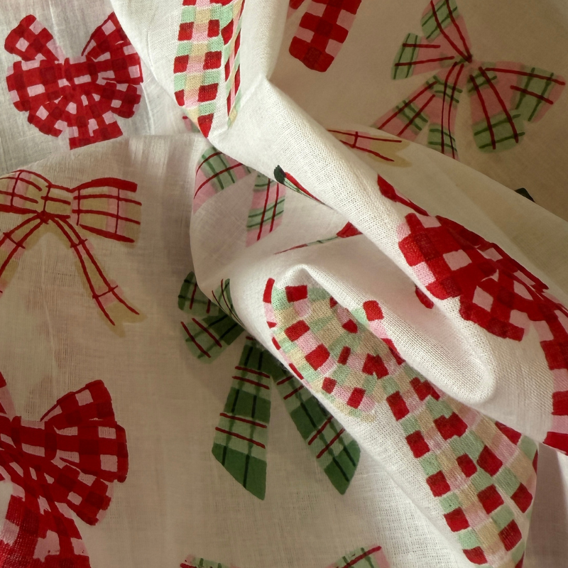 Close-up of fabric with red and green checkered bows on a beige background
