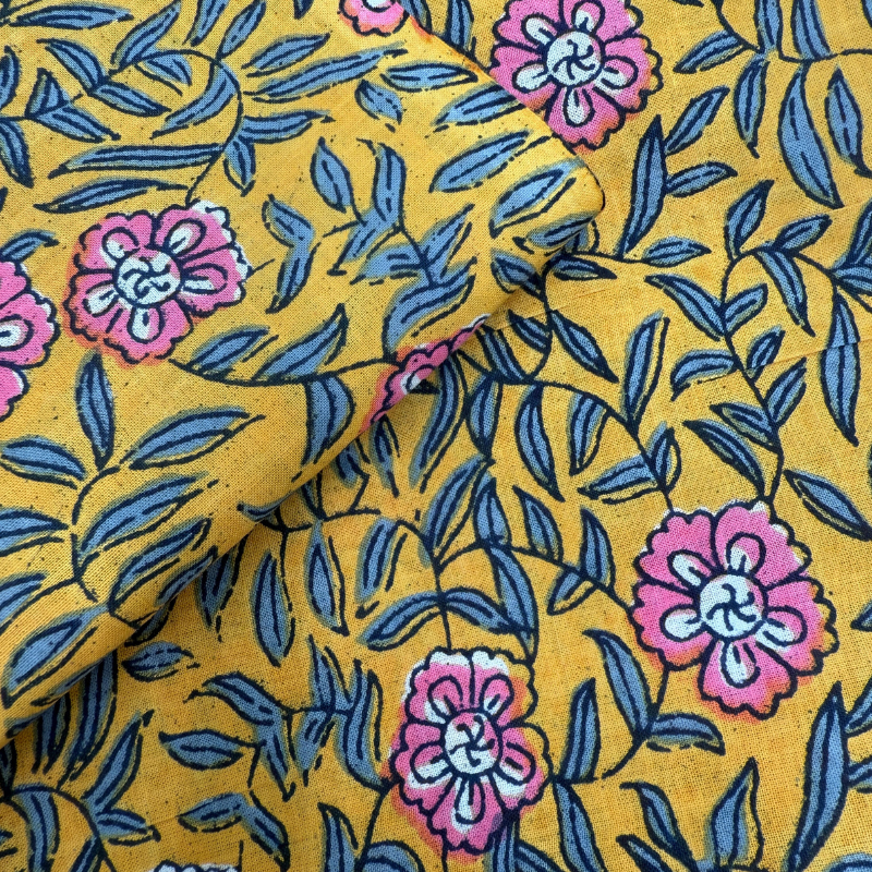 Floral fabric with pink flowers and blue leaves on a yellow background