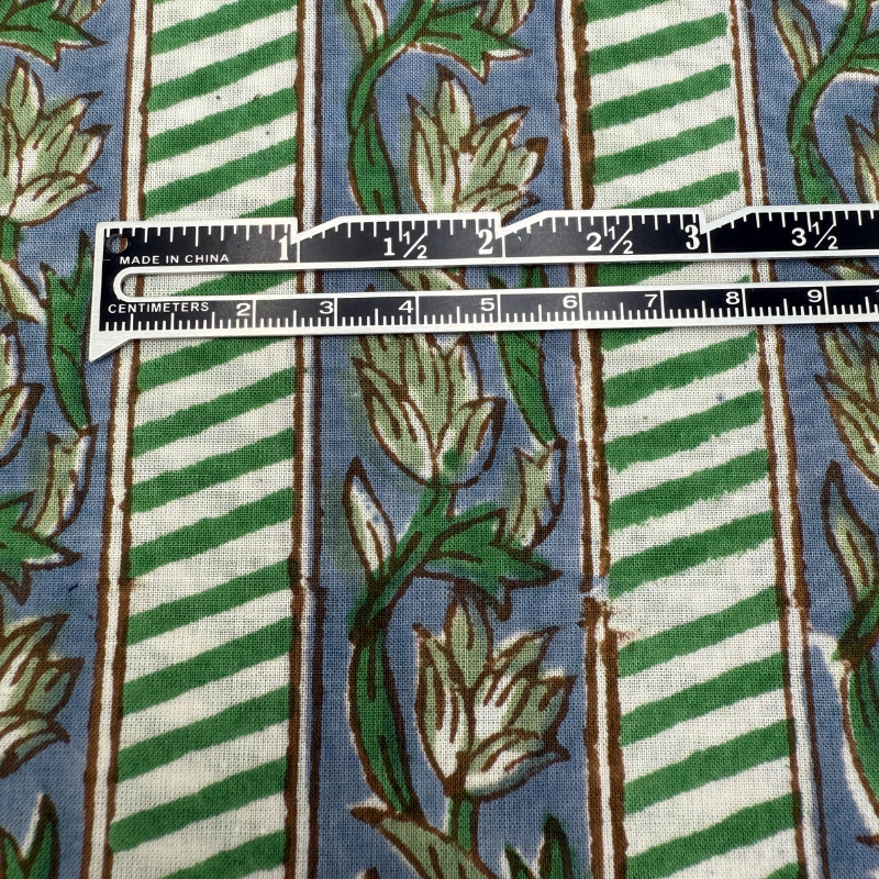 Fabric with green and white striped pattern and floral design, ruler for scale.