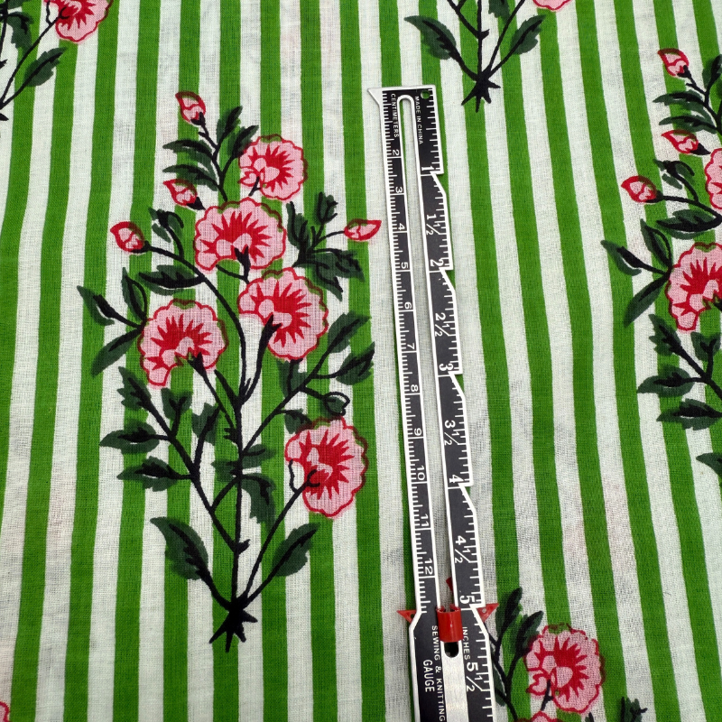 Fabric with green and white stripes and pink floral patterns, featuring a ruler for scale.
