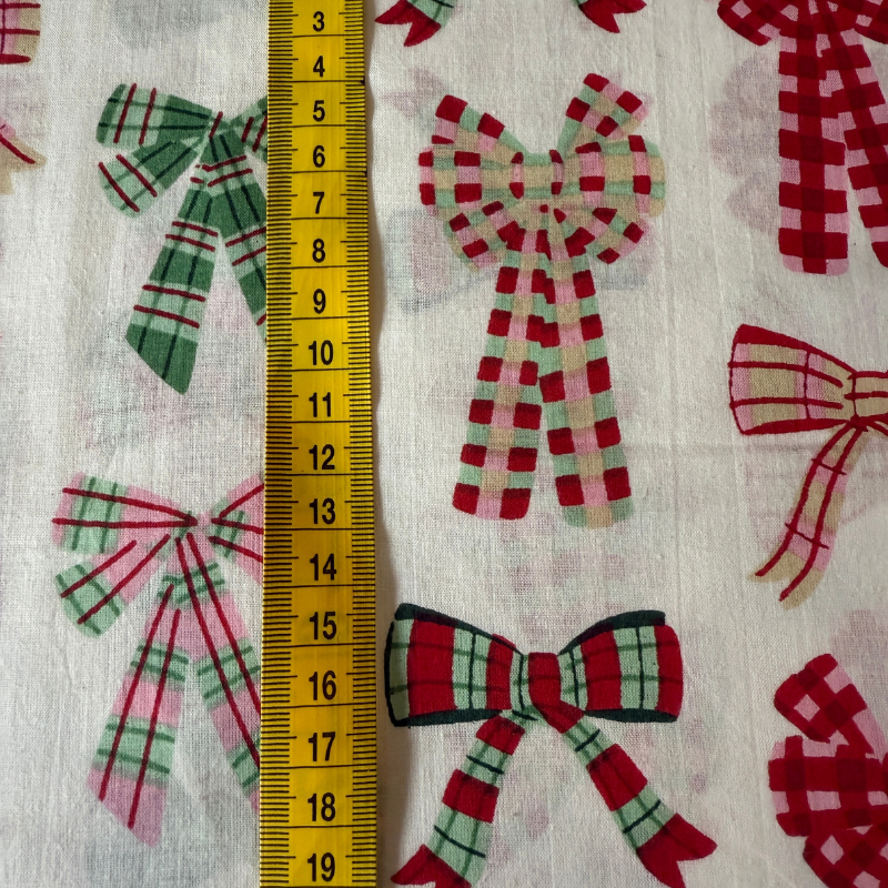 Fabric with plaid bows pattern and a ruler for scale on a white background