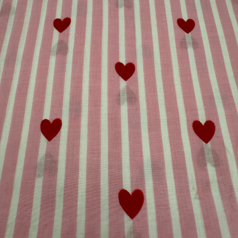 Fabric with red heart shapes on a striped pink and white background