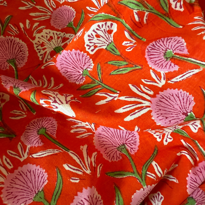 Floral pattern on orange fabric with pink flowers and green leaves