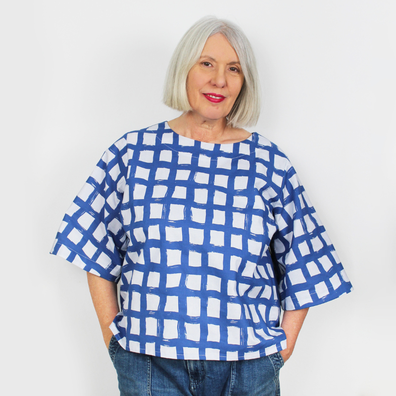 Woman wearing a blue and white checkered shirt against a plain background