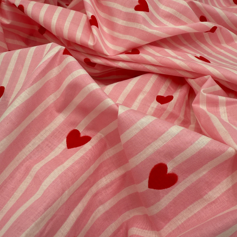 Pink fabric with white stripes and red hearts