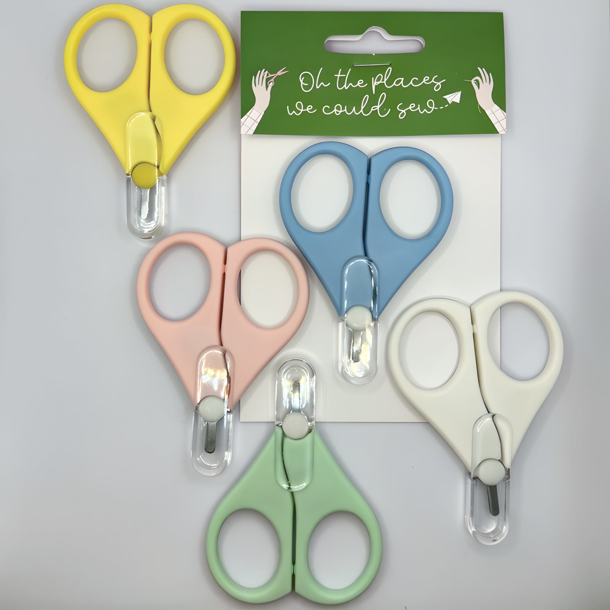 Set of colourful travel scissors with the minimalist packaging in the background.