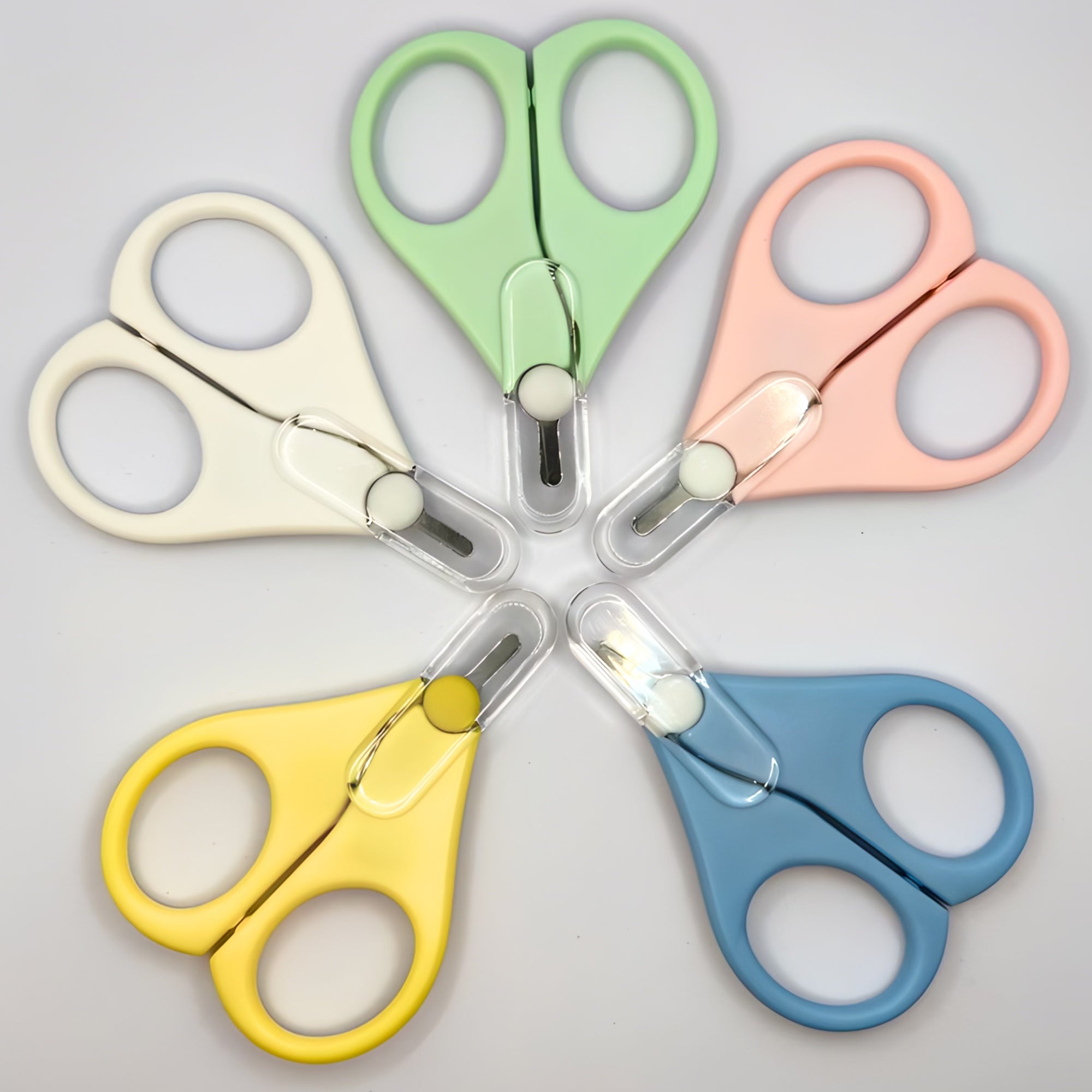 Set of colourful travel scissors arranged in a circle on a light background