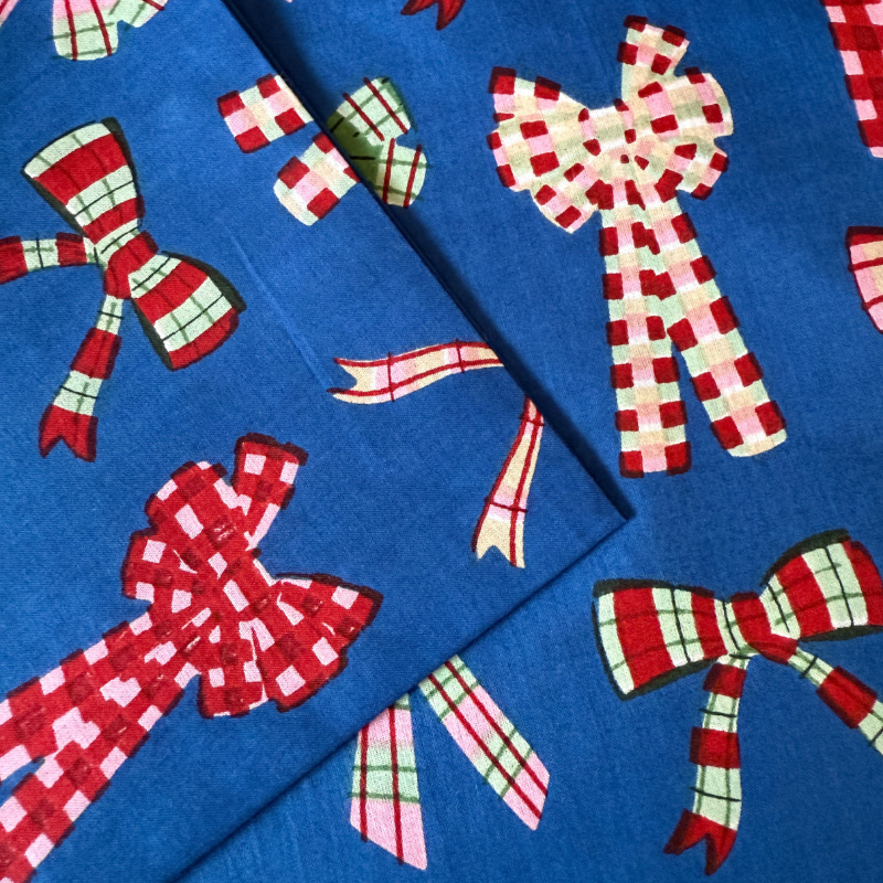 Blue fabric with red and green checkered bows on a blue background