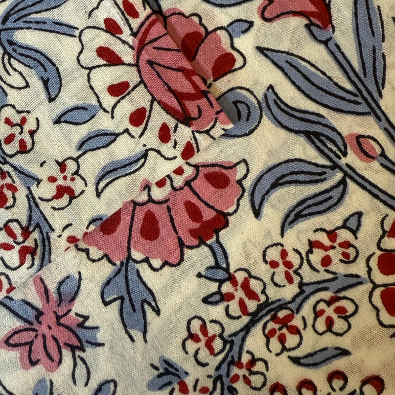 Close-up of floral patterned fabric with red, blue, and beige colors.