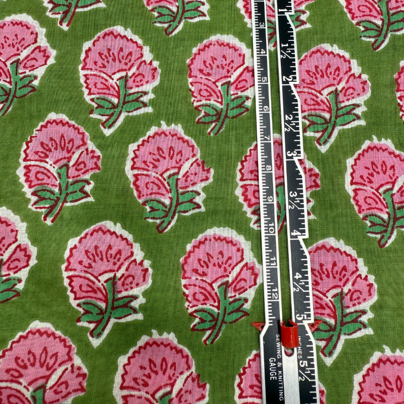 Fabric with pink floral pattern on a green background, measured with a ruler.