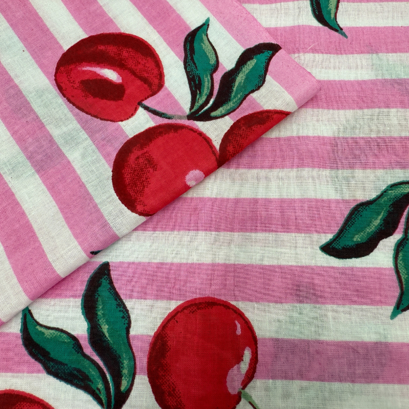 Fabric with red cherry design on pink and white striped background