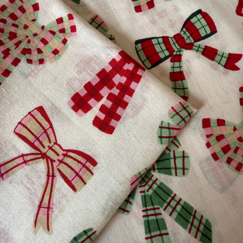 Fabric with red, green, and pink plaid bows on a white background
