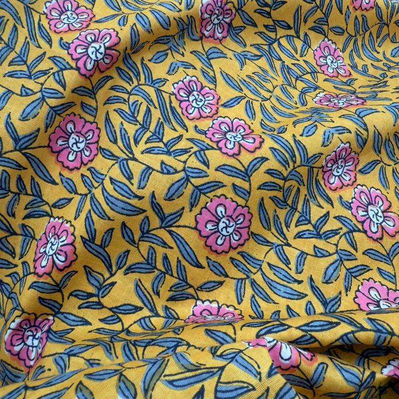 Floral fabric pattern with pink flowers and blue leaves on a yellow background