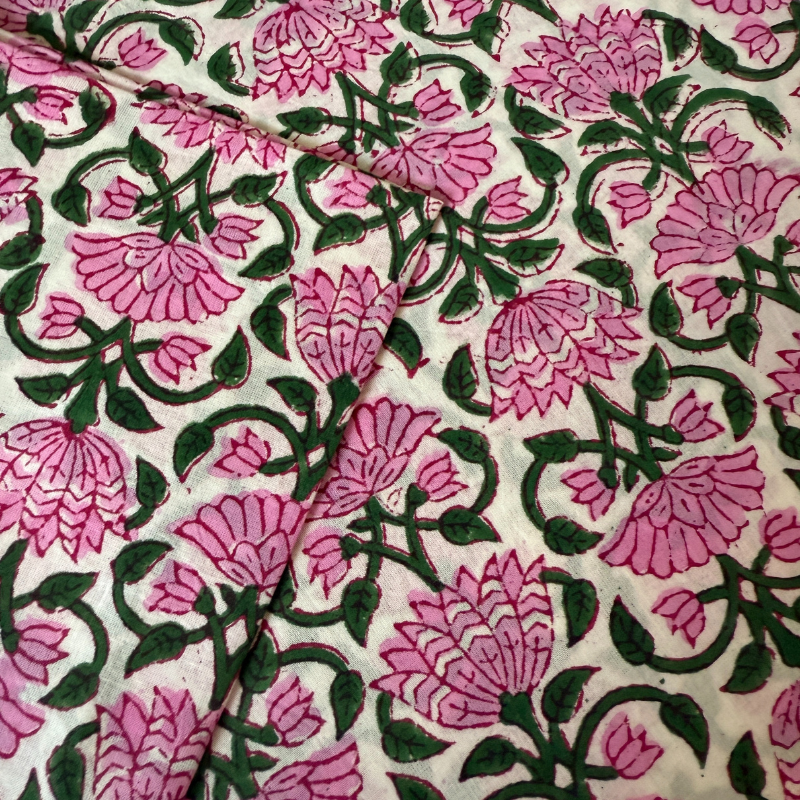Floral patterned fabric with pink flowers and green leaves on a white background