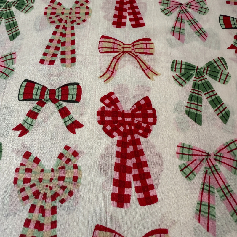 Pattern of red, green, and pink plaid bows on a textured fabric background