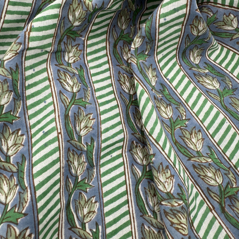 Patterned fabric with green and white stripes and floral designs on a blue background