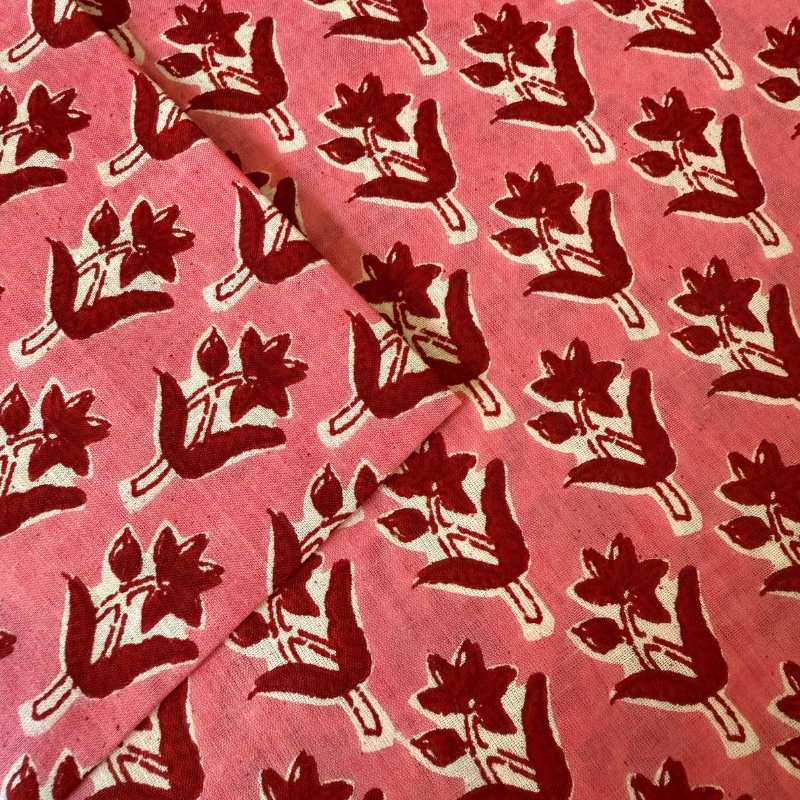 Red floral pattern on a pink fabric background