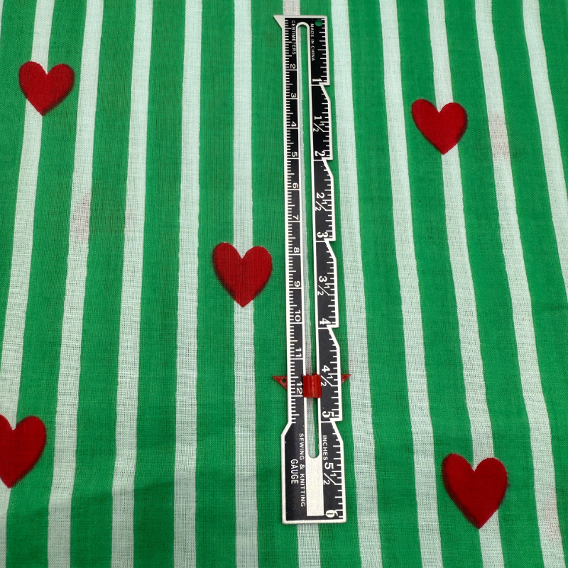 Ruler on a green and white striped fabric with red hearts