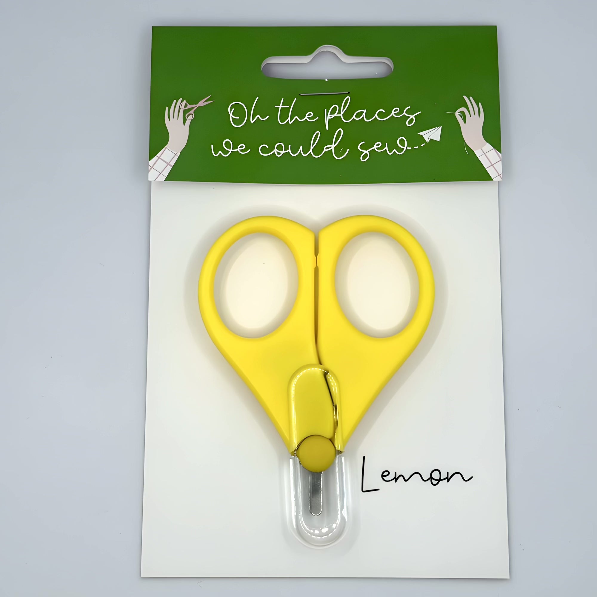 Yellow scissors in packaging with a green label on a gray background