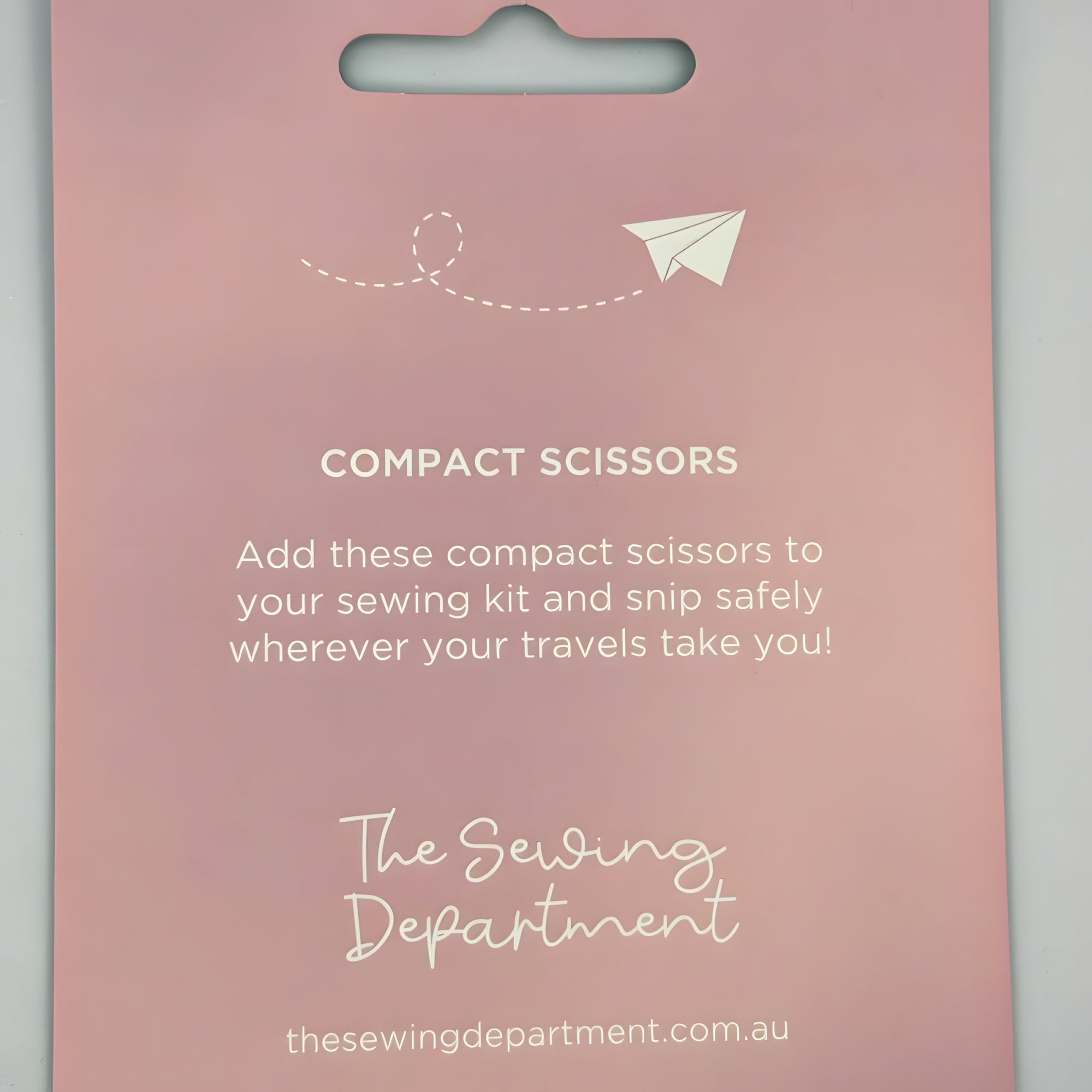 Compact scissors packaging with text on a pink background